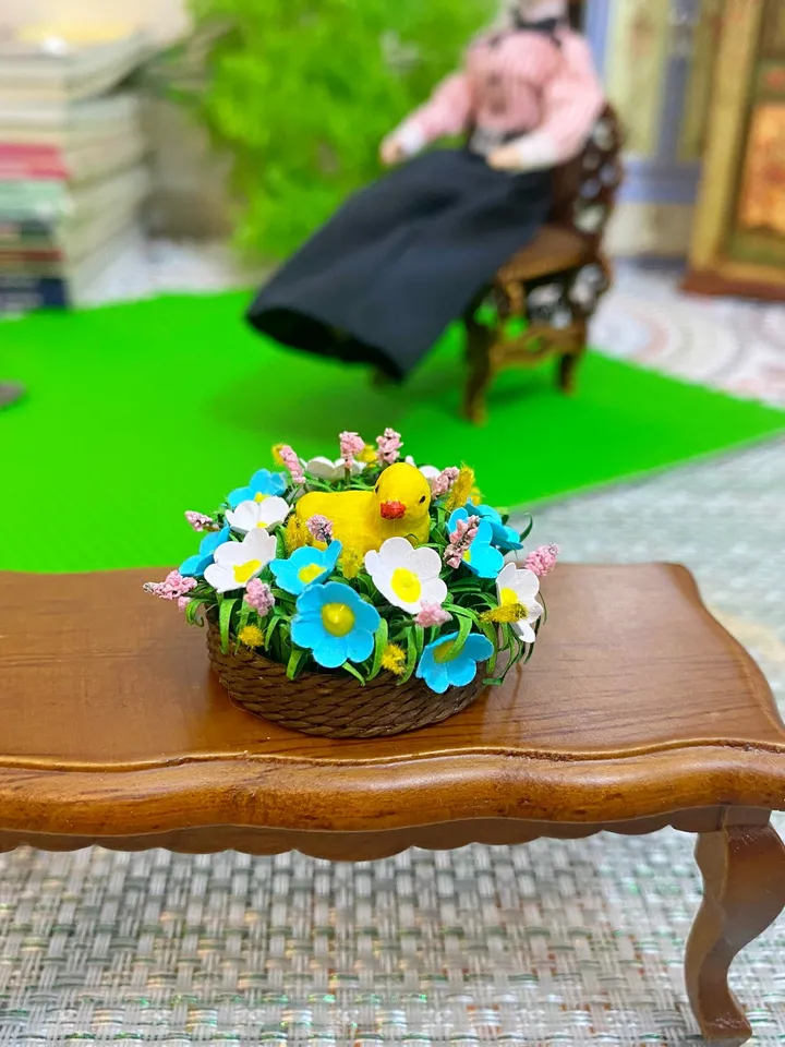 Easter miniature.Chicken in a basket with flowers.