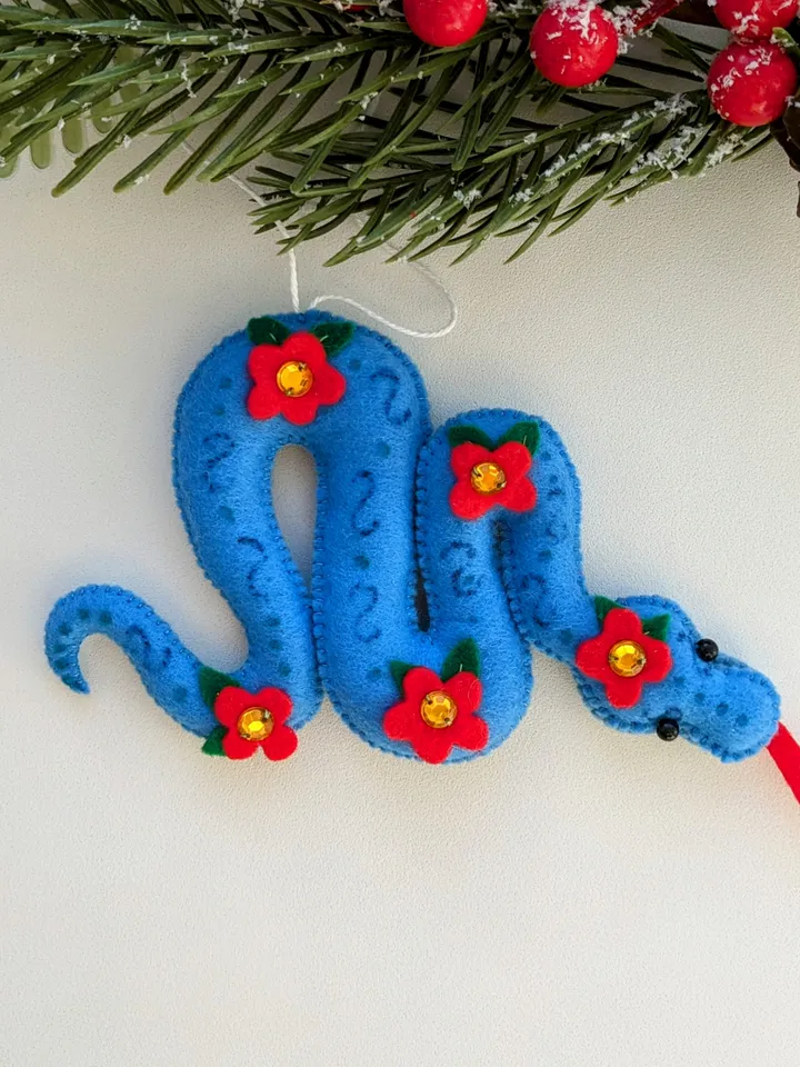A blue snake in a red flower is a symbol of the new year 2025 according to the eastern calendar. Cute felt snake - Christmas tree decoration, Christmas gift