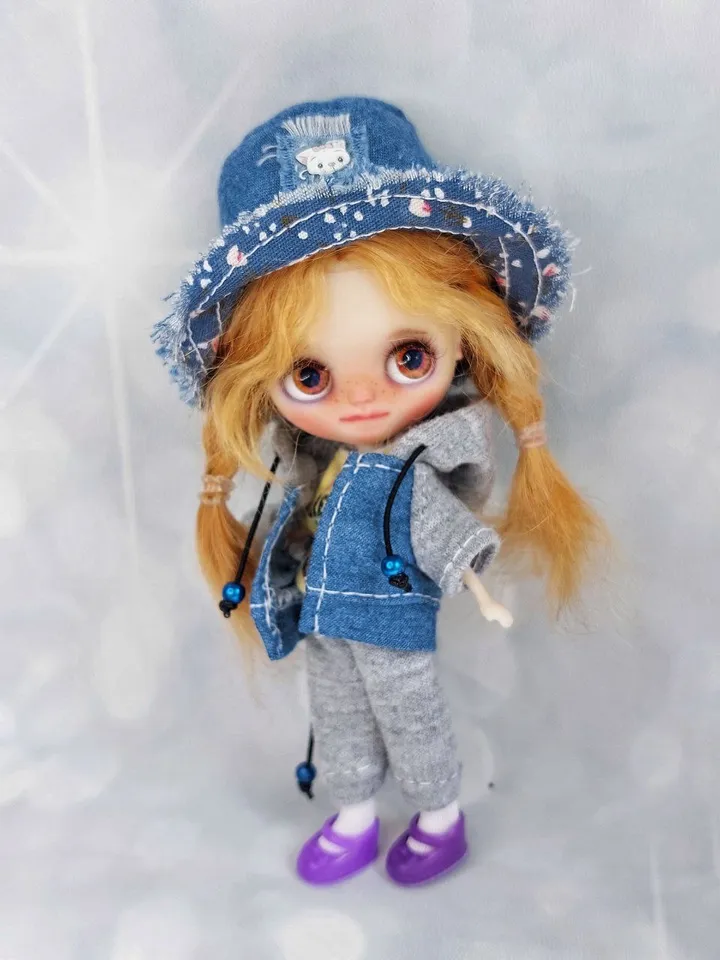 A little Blythe doll with red hair and brown eyes. a girl in a denim outfit.