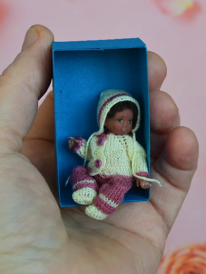 Miniature doll child in 12th scales. A baby for the dollhouse. Baby in a knitted suit.