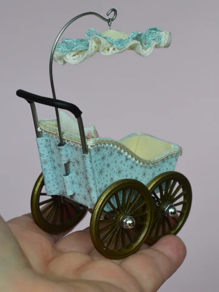 Miniature toy stroller for a little doll. Pram for the little poopsie.