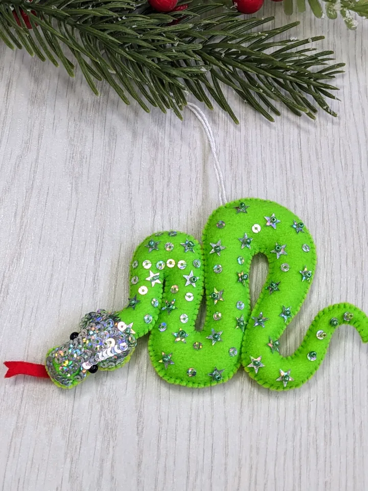 The green snake, the emerald snake, is the symbol of the new year 2025 according to the eastern calendar. Green snake with shiny scales felt Christmas tree decoration