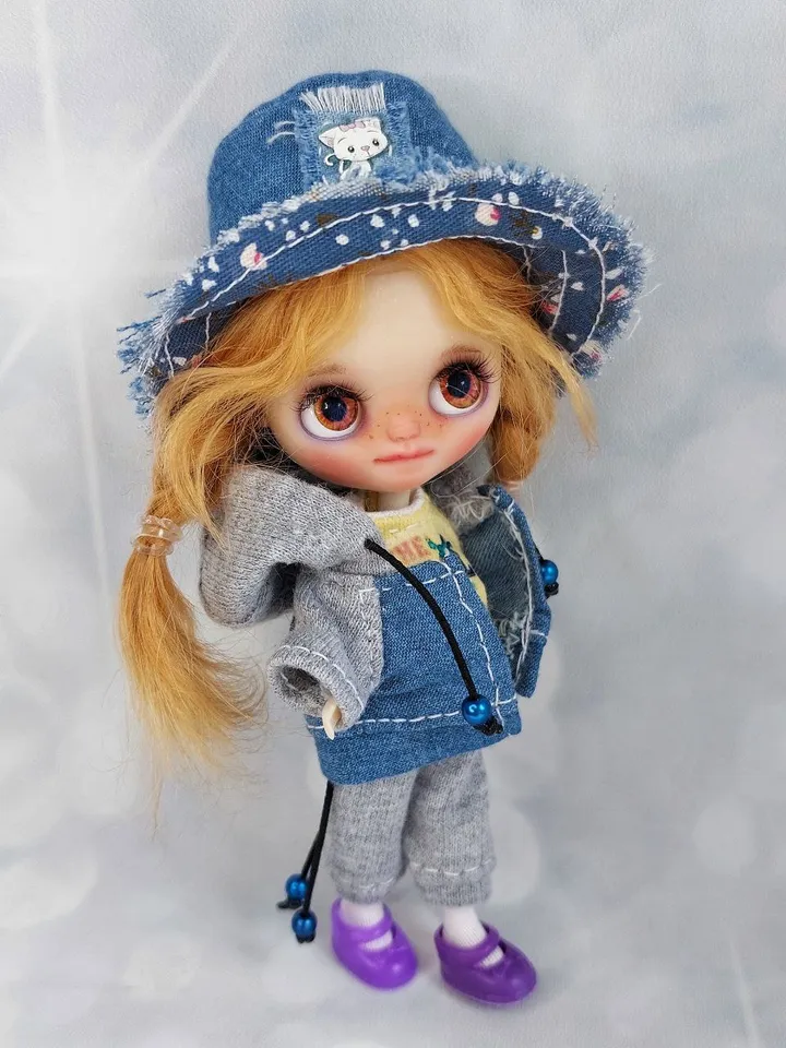A little Blythe doll with red hair and brown eyes. a girl in a denim outfit.
