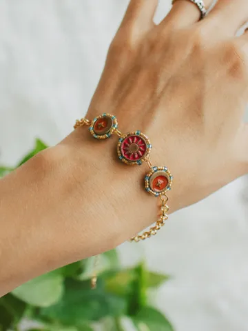 Charm bracelet When The Sun Meets The Moon on a thick chain. Gold stackable jewelry ith celestial design in sunset red and orange color with beading. Adjustable length. Maylina Soul $54.00
