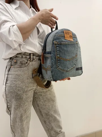 medium sized denim backpack made from recycled jeans for walking, studying, work, traveling. Backpack with 2 pockets outside and 3 pockets inside (1 with a zipper). Inside lining made of 100% cotton. Decorated with a label and a leather strip on the zippe $80.00